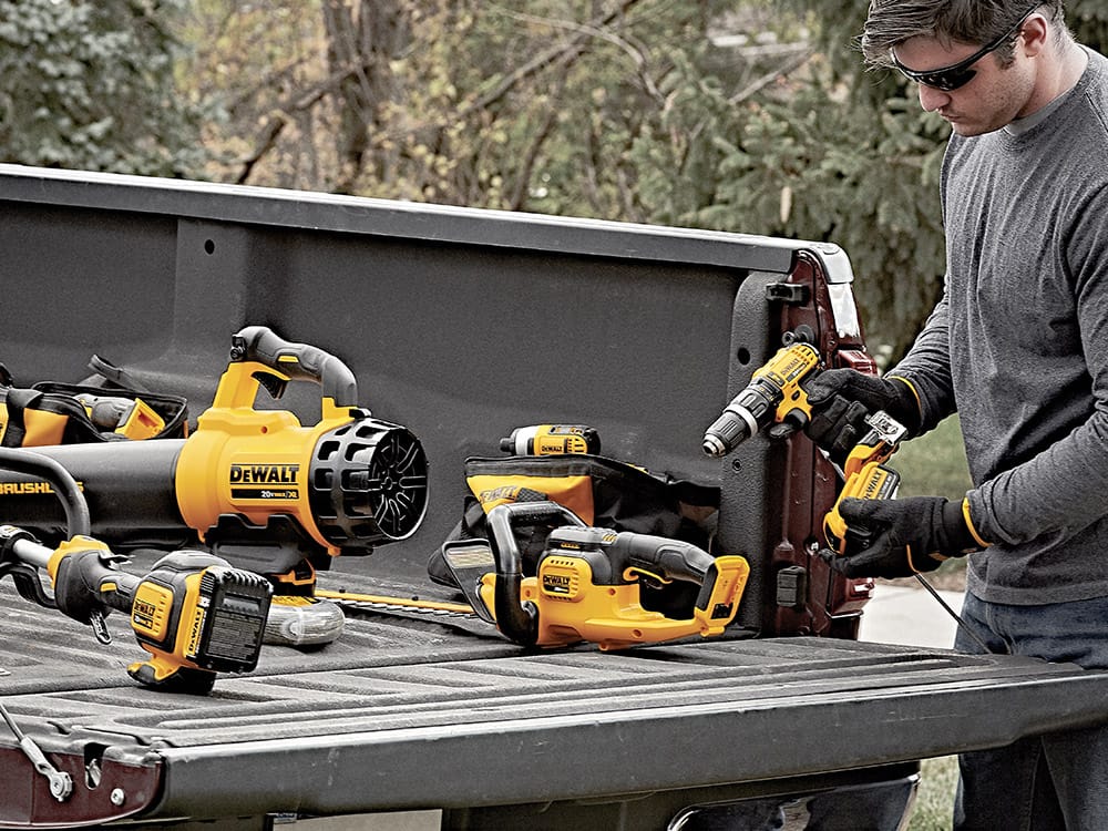 Man with a collection of DeWalt tools in a pick up truck bed